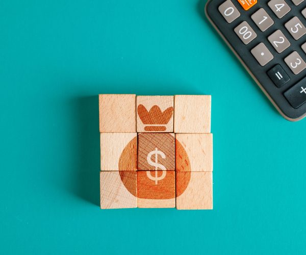 Financial concept with icon on wooden cubes, calculator on turquoise background flat lay.