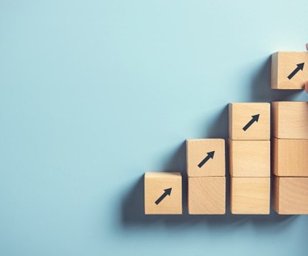 Close up man hand arranging wood block stacking as step stair on paper pink background. Business concept growth success process, copy space.